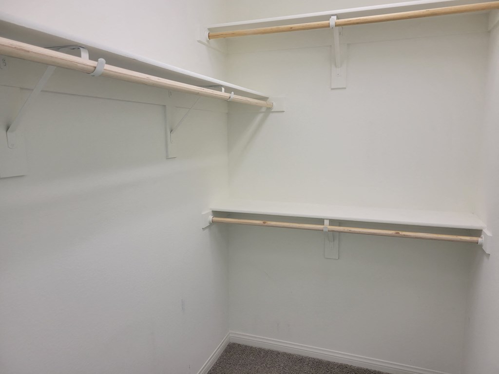 a walk in closet in a room with white walls and shelves