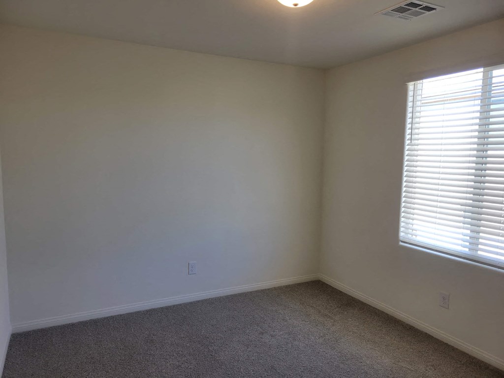 a room with white walls and a window with blinds