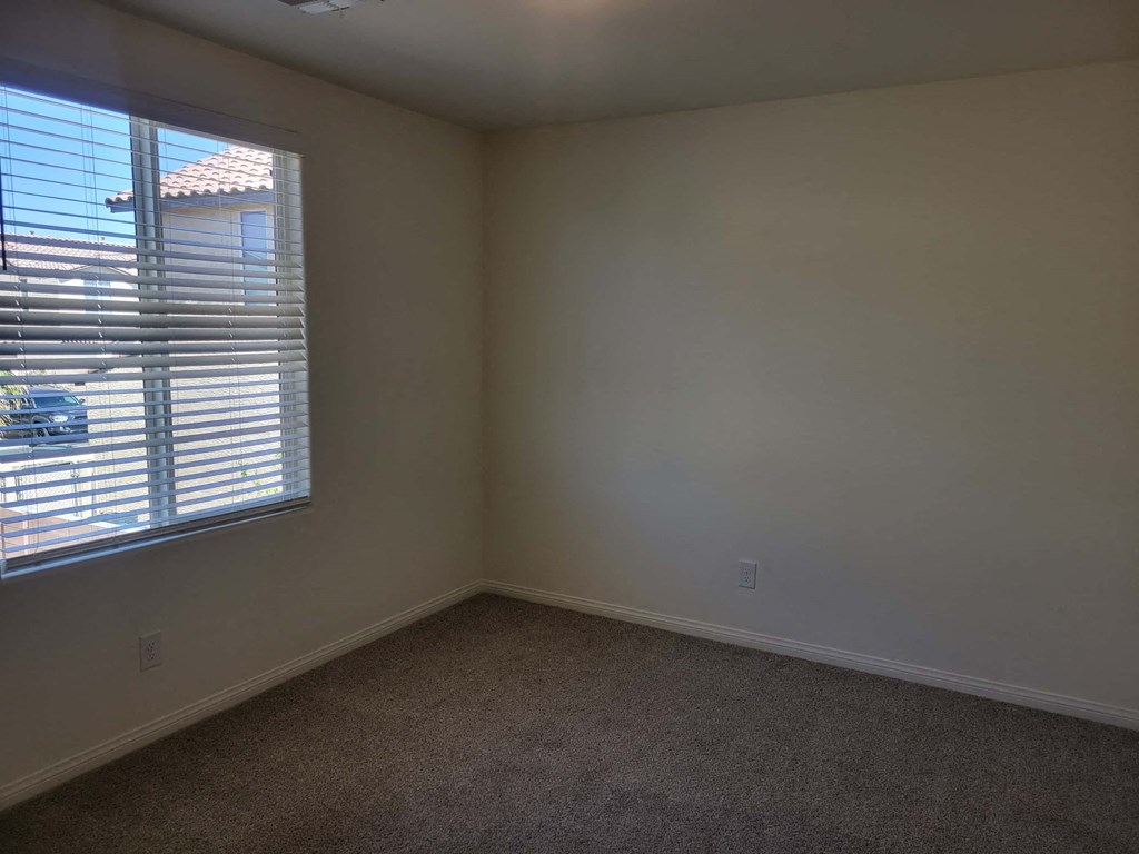 a bedroom with a large window and a carpet
