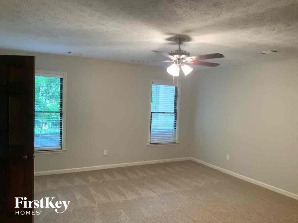 an empty living room with a ceiling fan and two windows