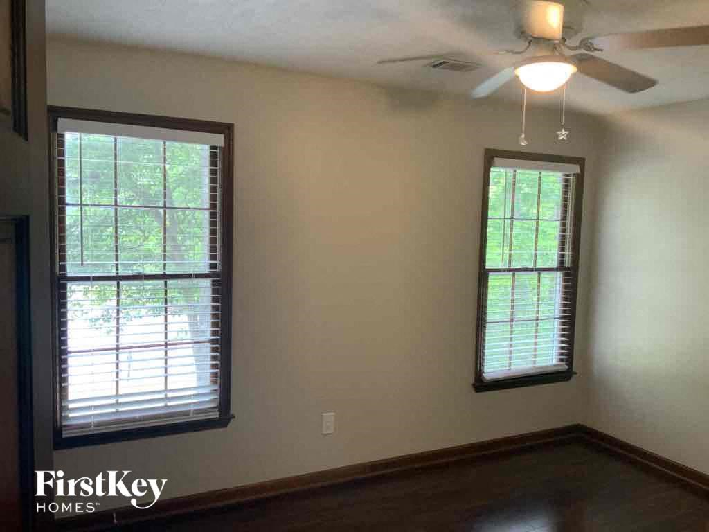 a living room with a ceiling fan and two windows