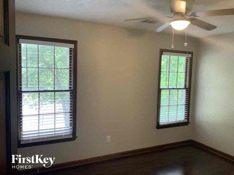 a living room with a ceiling fan and two windows