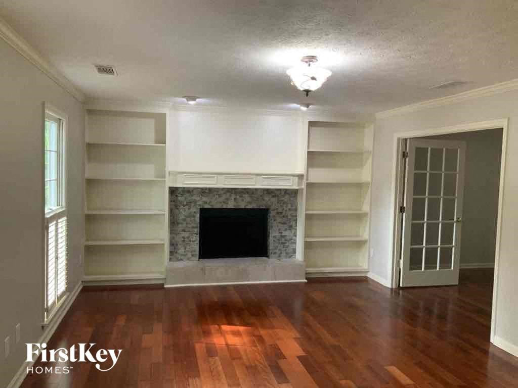 an empty living room with a fireplace and bookshelves