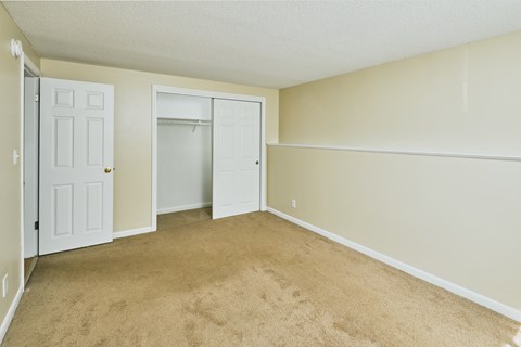 an empty living room with a closet and a door to the bathroom