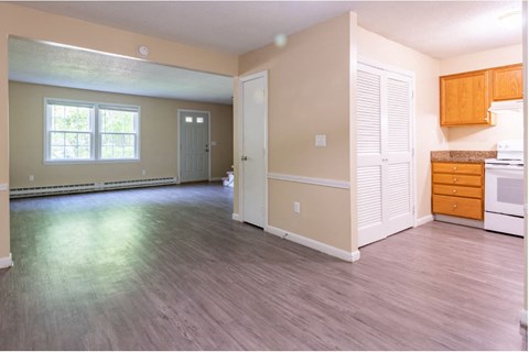 an empty living room and kitchen with wood floors