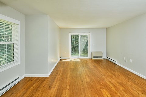an empty living room with wood floors and a window