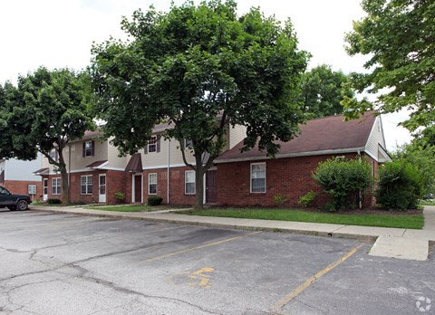 the front of a brick house with trees and a parking lot