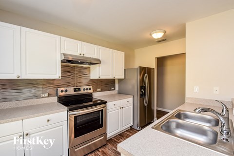 A kitchen with white cabinets and a stainless steel sink.