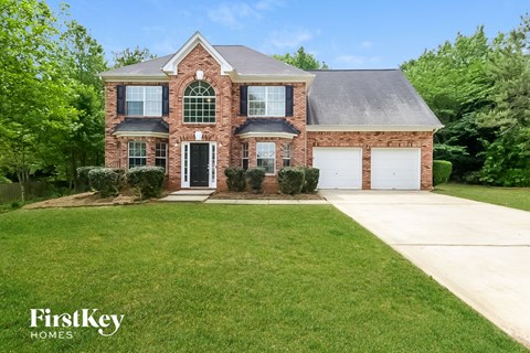 a brick house with a green lawn and a white garage
