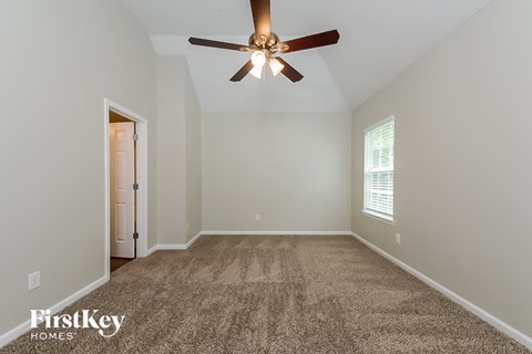 the master bedroom has a carpeted floor and a ceiling fan