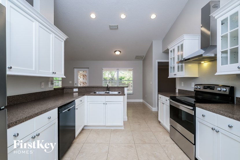 A kitchen with white cabinets and black appliances.