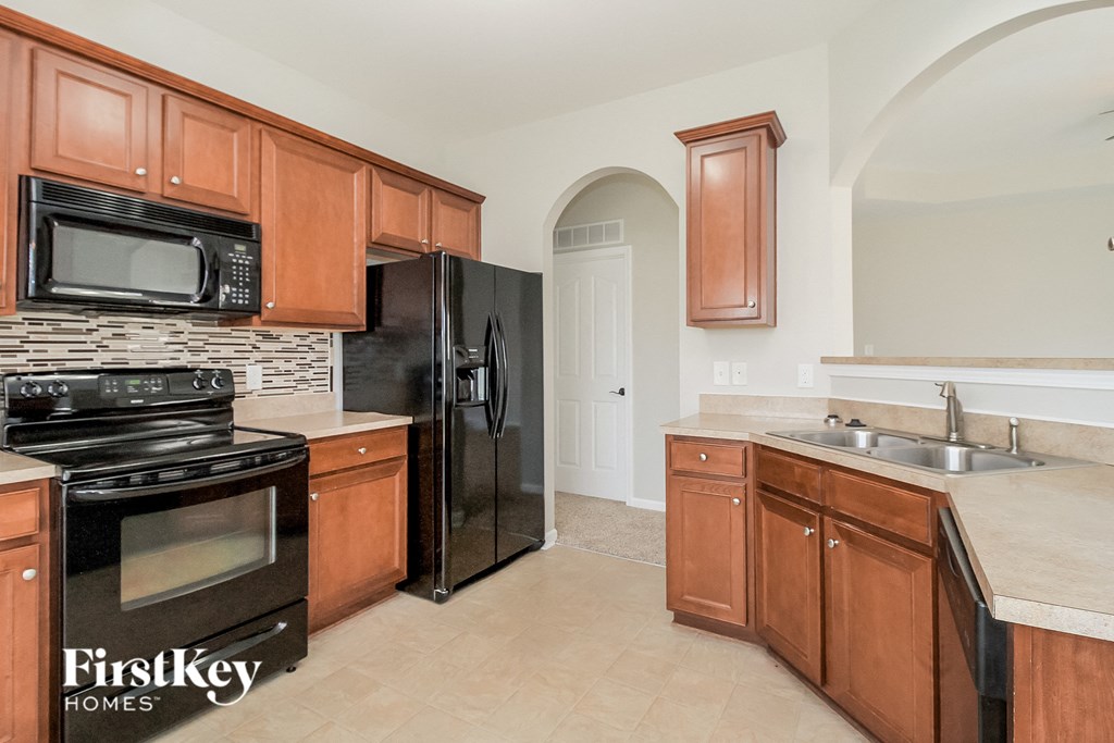 a kitchen with wood cabinets and black appliances and a black refrigerator