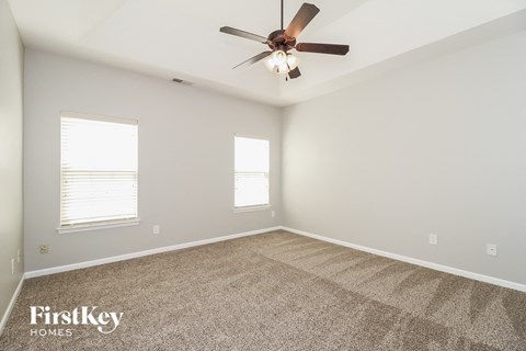 the spacious living room with ceiling fan and carpet