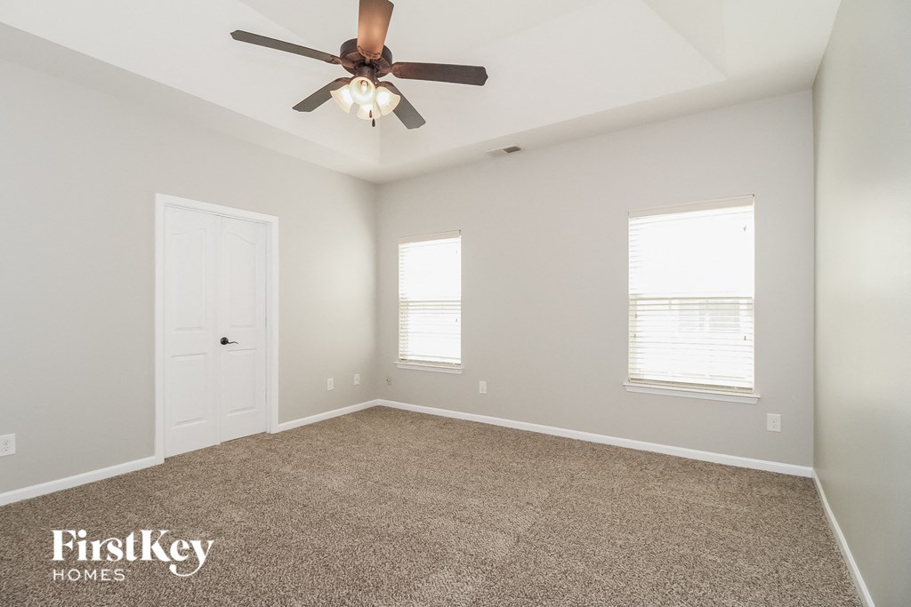 the master bedroom has a ceiling fan and a carpeted floor