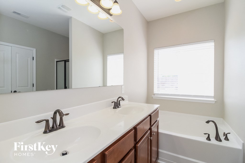 a bathroom with a sink and a tub and a large mirror