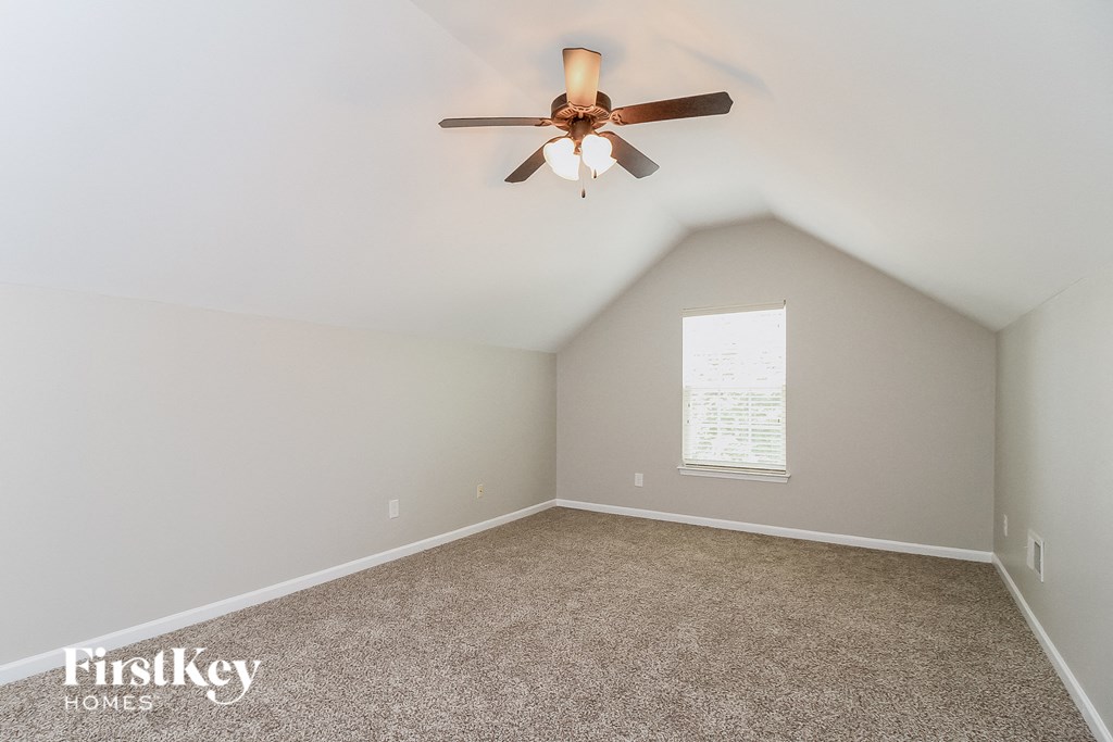 the master bedroom has a ceiling fan and a carpet