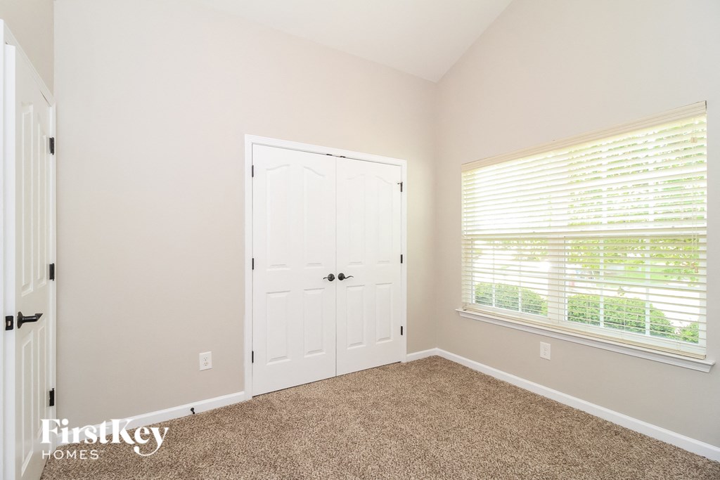 a bedroom with a door and a window and a carpeted floor