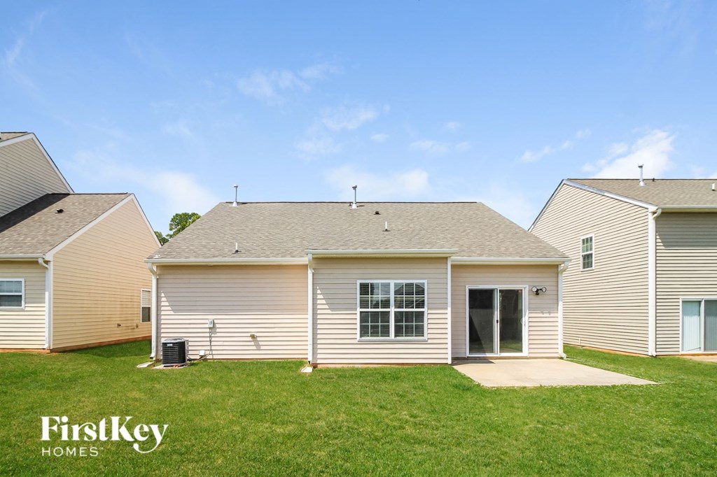a small white house with a grassy yard and two neighboring houses