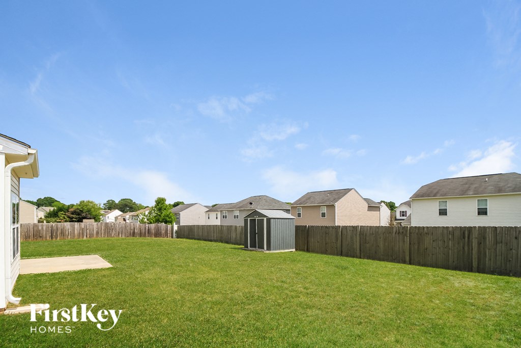 a backyard with a fence and a shed in front of houses