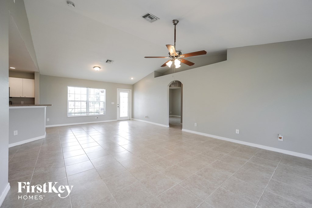 A spacious room with a ceiling fan and tiled flooring.
