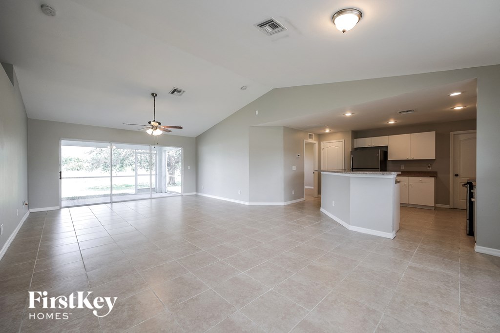 A spacious living room with a kitchen in the background.