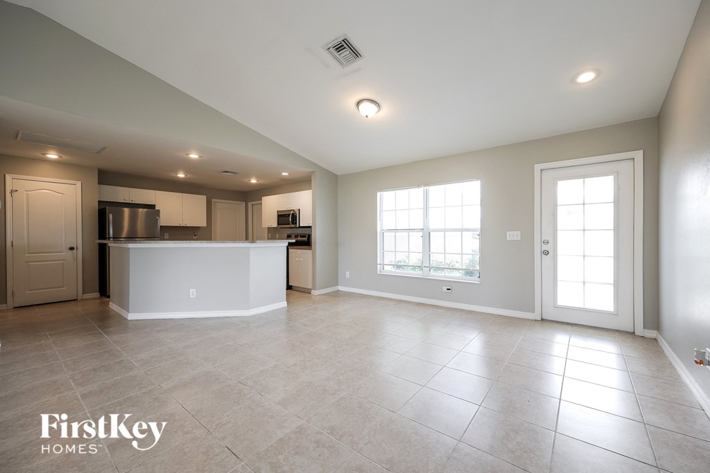 A spacious kitchen and living room with a white countertop and tile flooring.