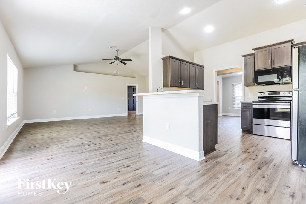 an open kitchen and living room with wood flooring and white walls