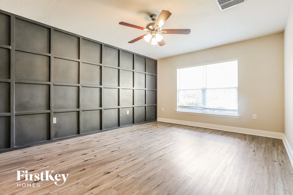 an empty living room with a ceiling fan and a window