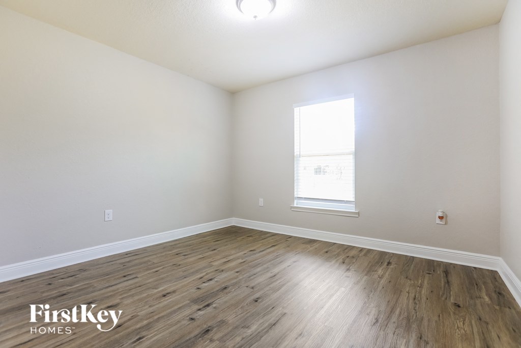 the living room with wood floors and white walls and a window