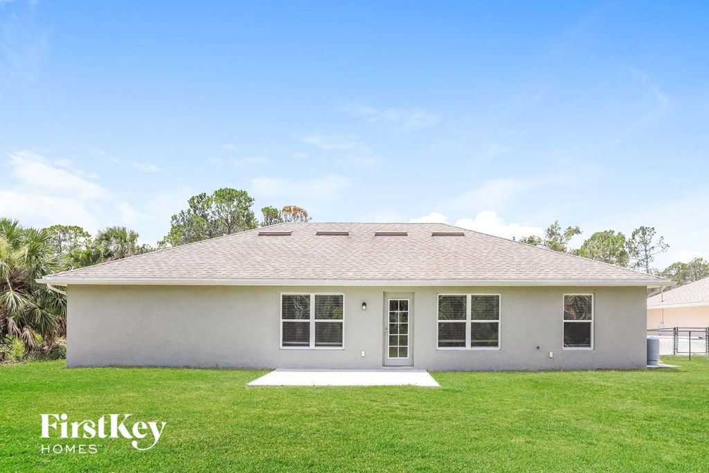 front view of a white house with a lawn and trees