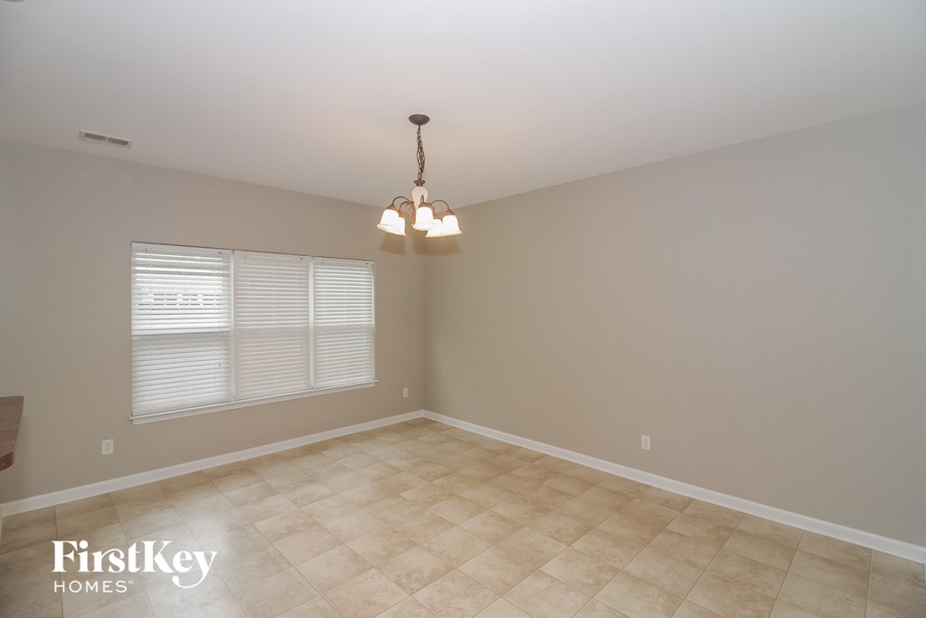 an empty dining room with a chandelier and a window