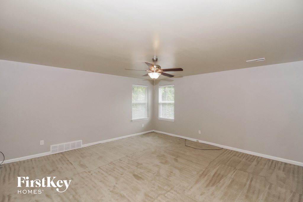 the spacious living room with wood floors and a ceiling fan