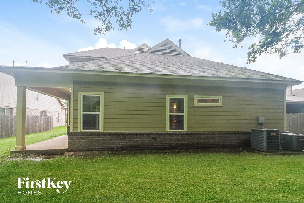 the front of a green house with a yard and a porch