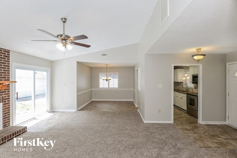 A spacious living room with a ceiling fan and a view of the kitchen.