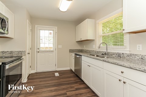 A kitchen with white cabinets and a granite countertop.
