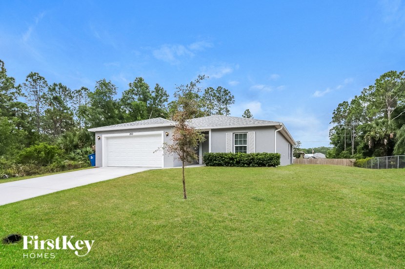 A house with a garage and a tree in the front yard.