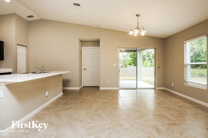 A spacious room with a bar area and sliding glass doors leading to a backyard.