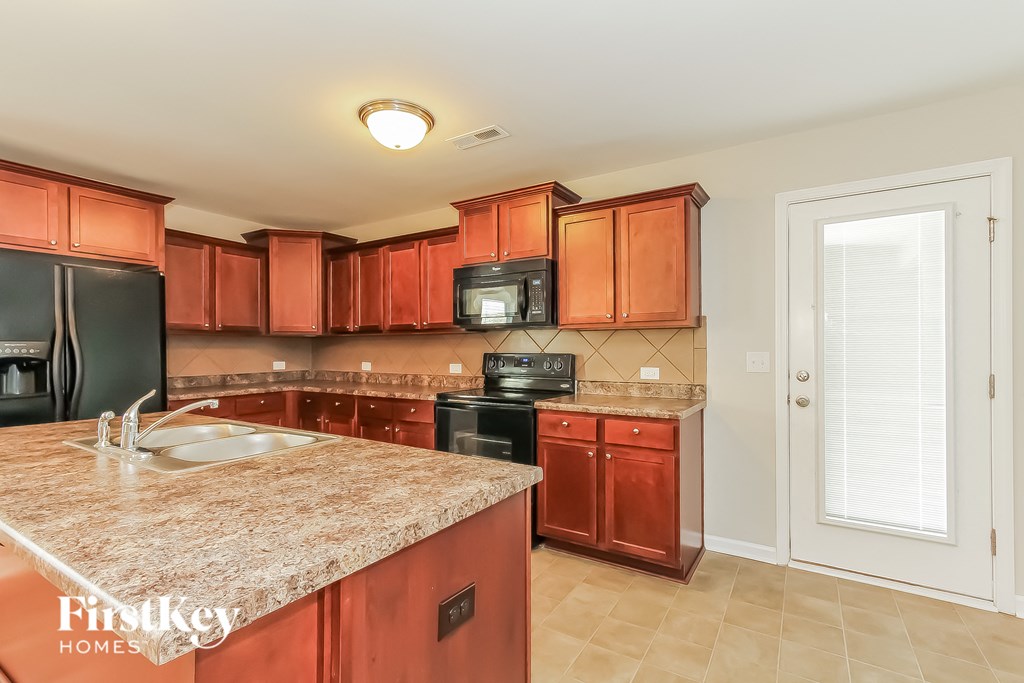 A kitchen with a granite countertop and wooden cabinets.