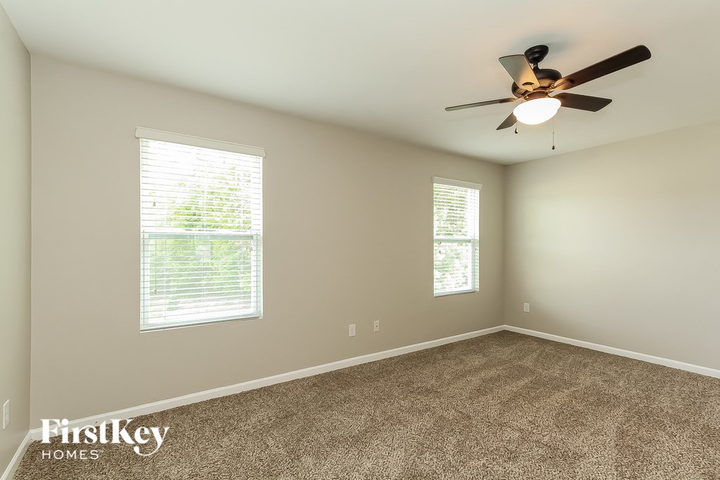 A room with a ceiling fan and two windows.
