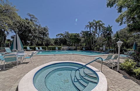 a swimming pool with chairs and a spa and trees