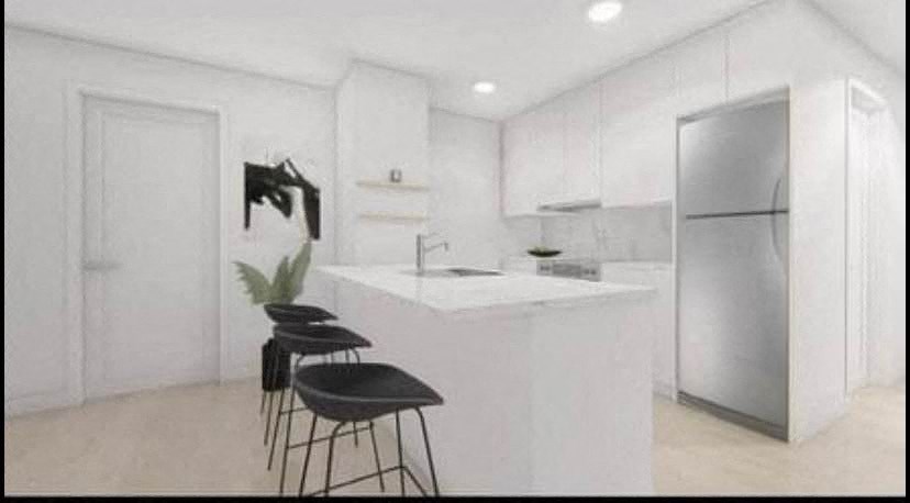 A kitchen with white cabinets and a black chair.