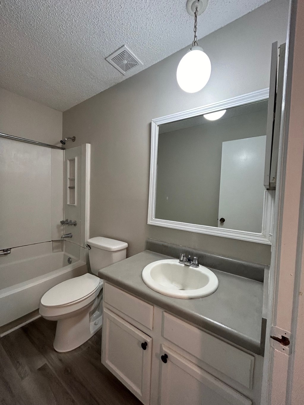 A bathroom with a toilet, sink, and mirror.