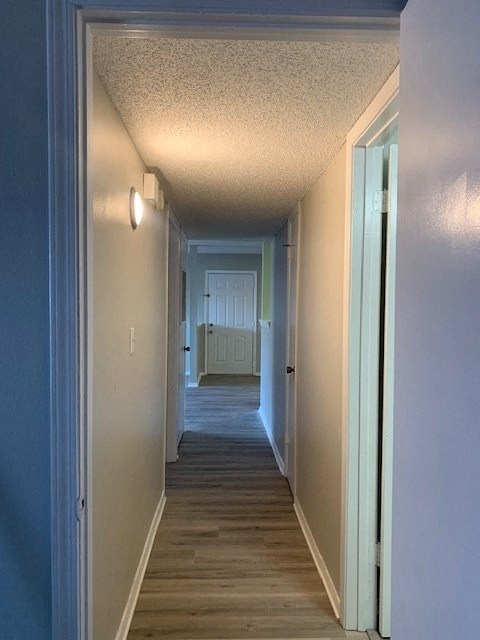 A long hallway with a white door at the end.