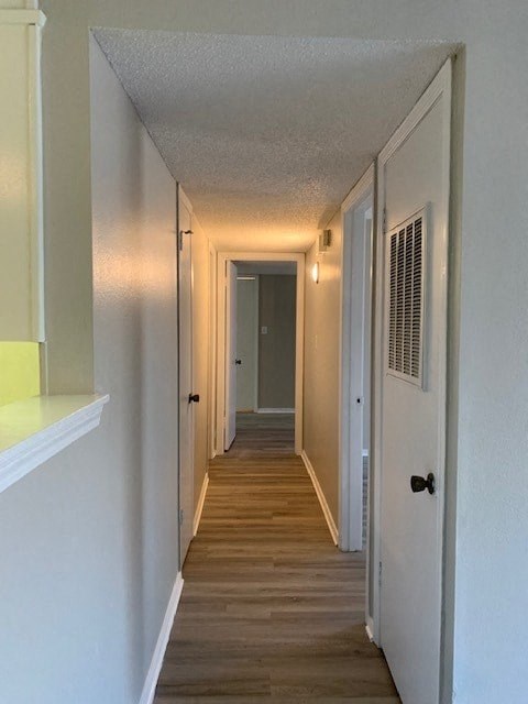 A long hallway with white walls and wood floors.