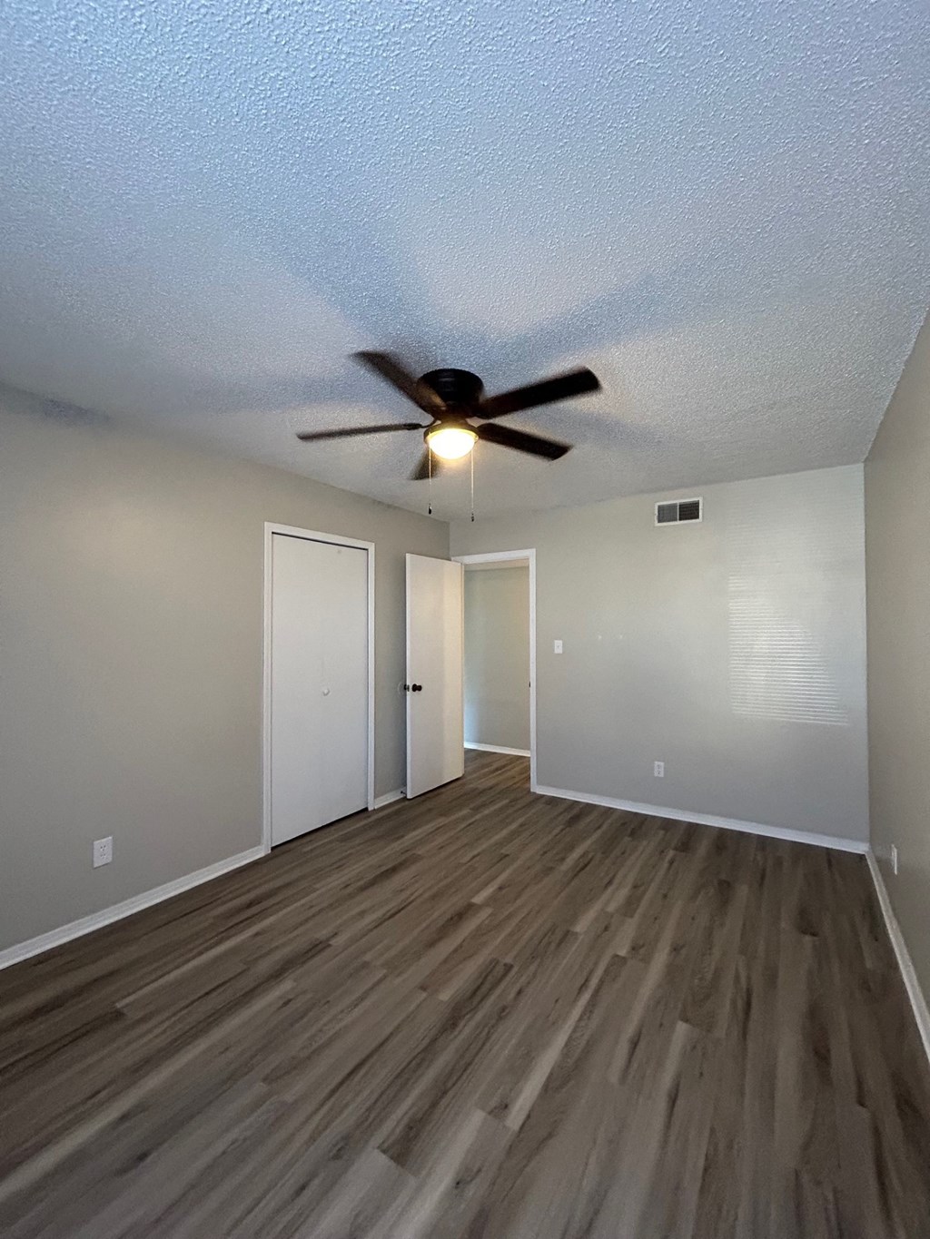 A room with a ceiling fan and wooden flooring.