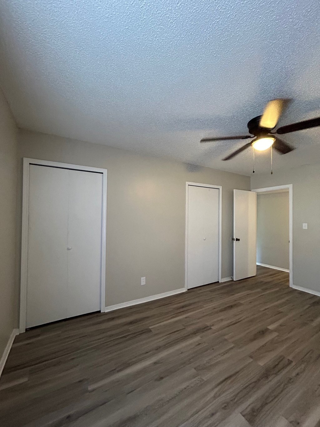 A room with a ceiling fan and three doors.