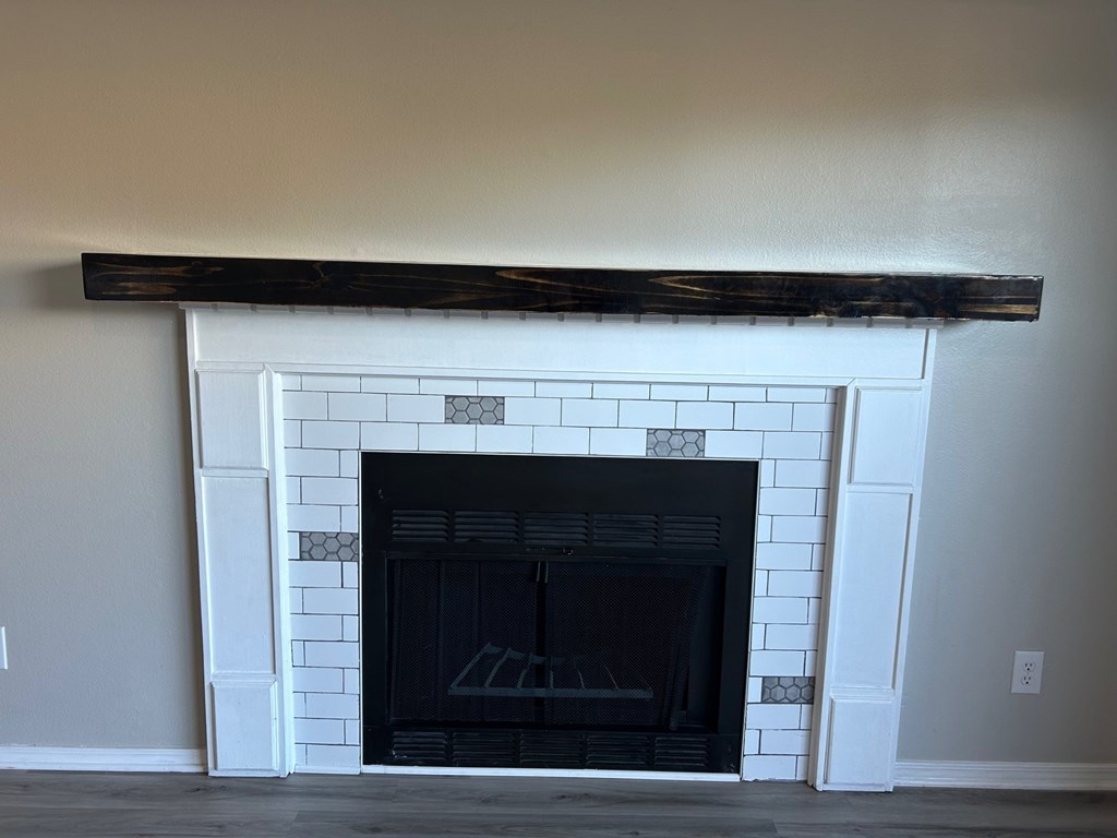 A fireplace with a black mantle and a white tile surround.