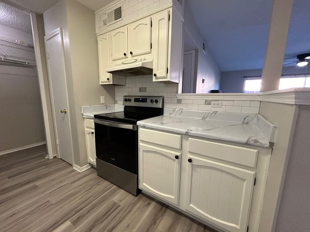 A kitchen with a black stove top oven and white cabinets.