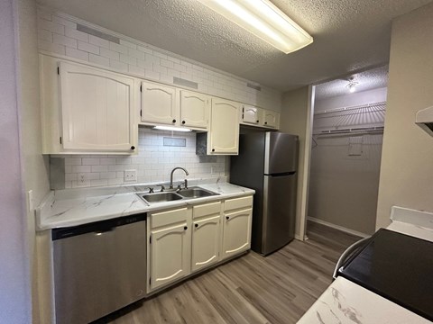 A kitchen with white cabinets and a black fridge.