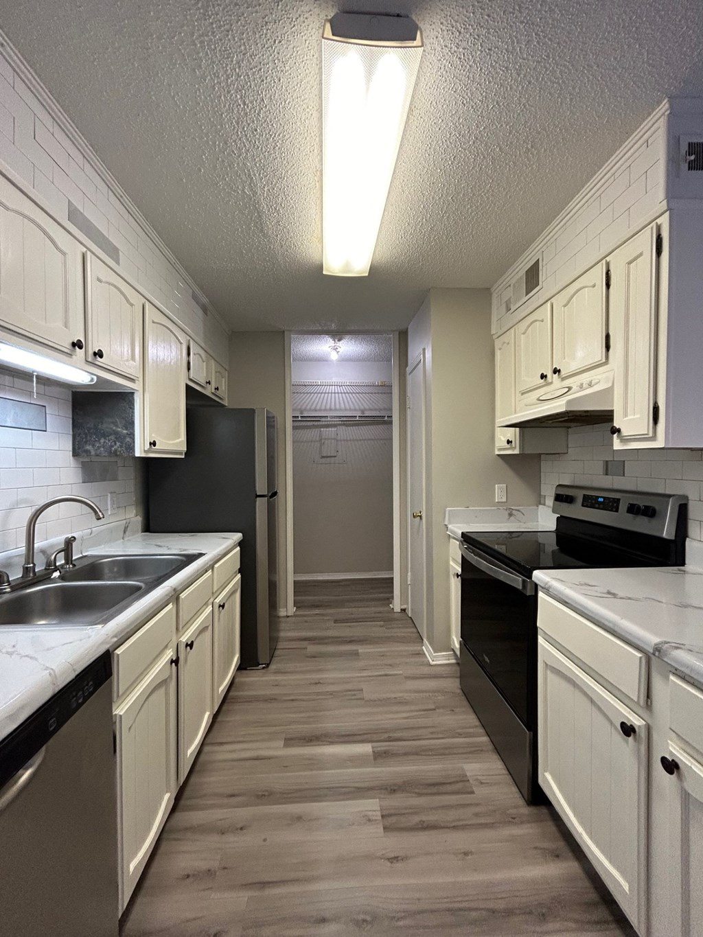 A kitchen with white cabinets and black appliances.